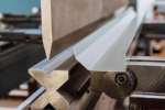 Close-up of a metalworking machine bending a sheet of metal with precision