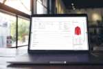 Laptop zeigt TRIMIT PDM mit Produktdaten, Varianten und Artikelinformationen für Mode- und Bekleidungsunternehmen.