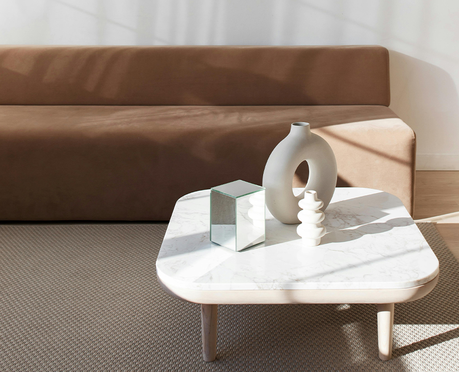 A modern showroom, with a marble table and a brown sofa, soft colored decorative elements on the table