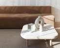 A modern showroom, with a marble table and a brown sofa, soft colored decorative elements on the table